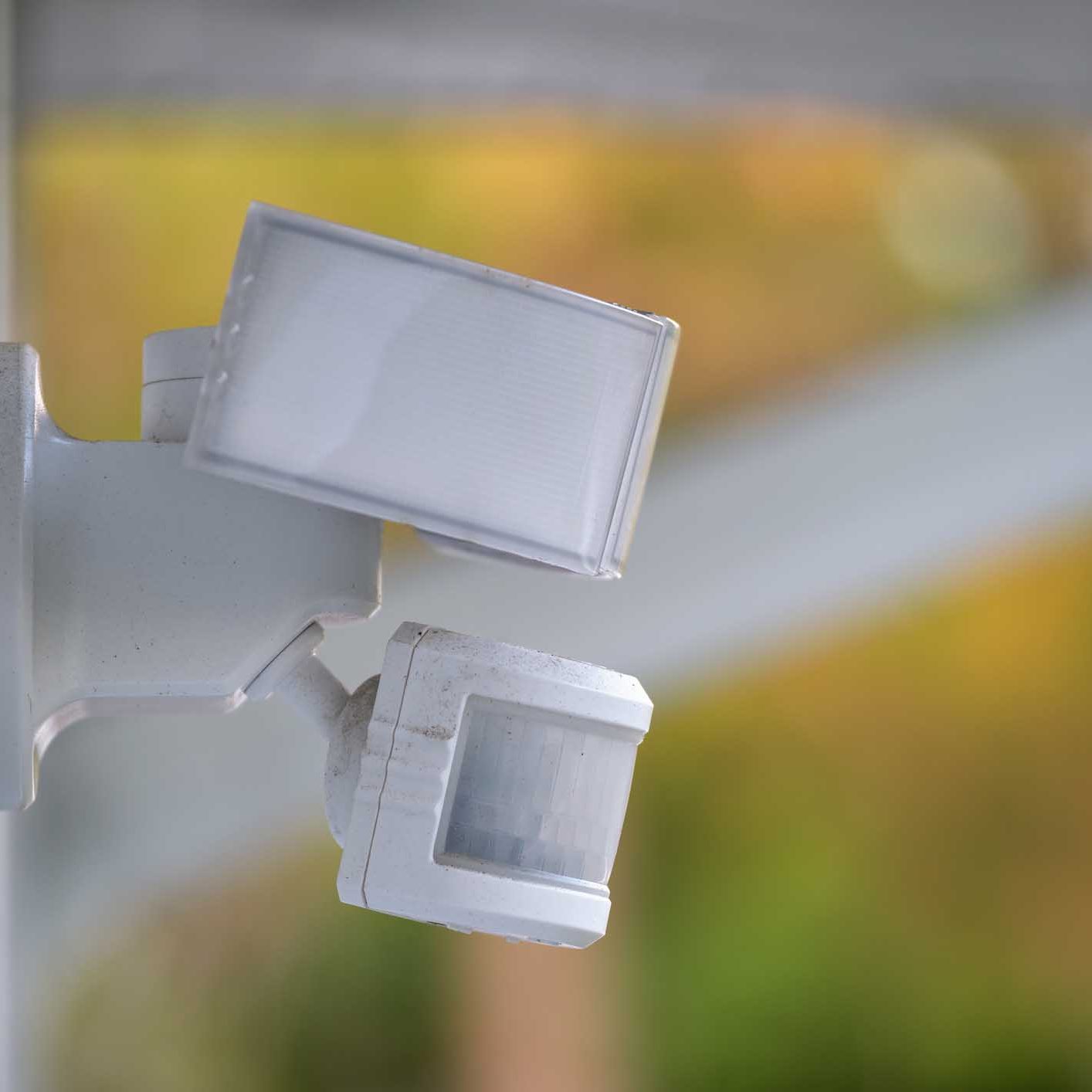 Woman monitoring modern cctv cameras on smartphone indoors, closeup. Home security system