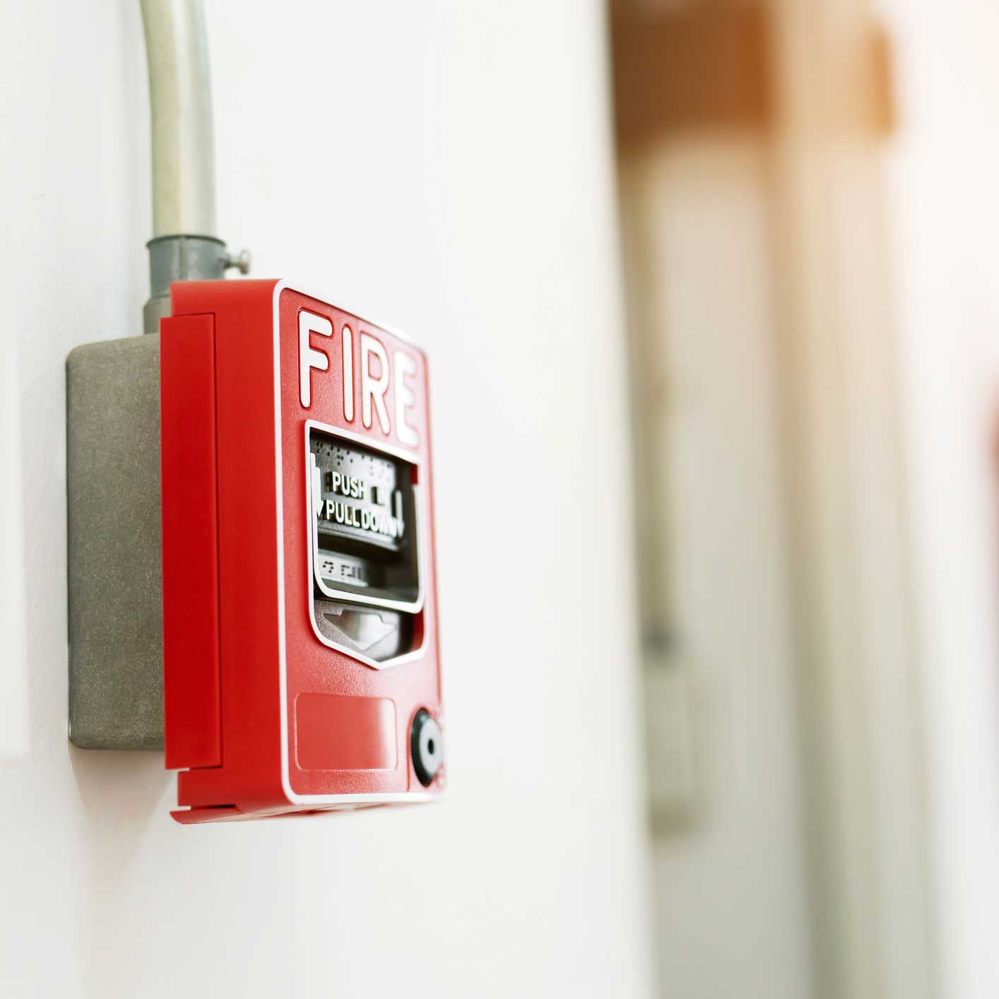 Manual pull fire alarm switch safety system box installed and fire extinguisher on white wall background.